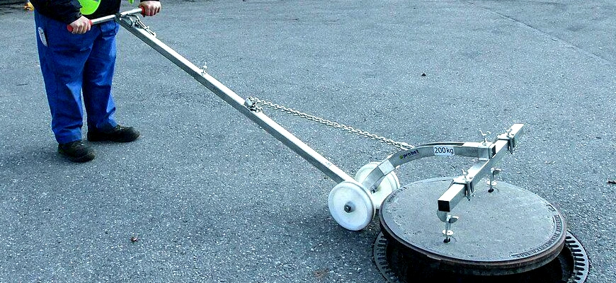 Surveyor lifting manhole cover safely